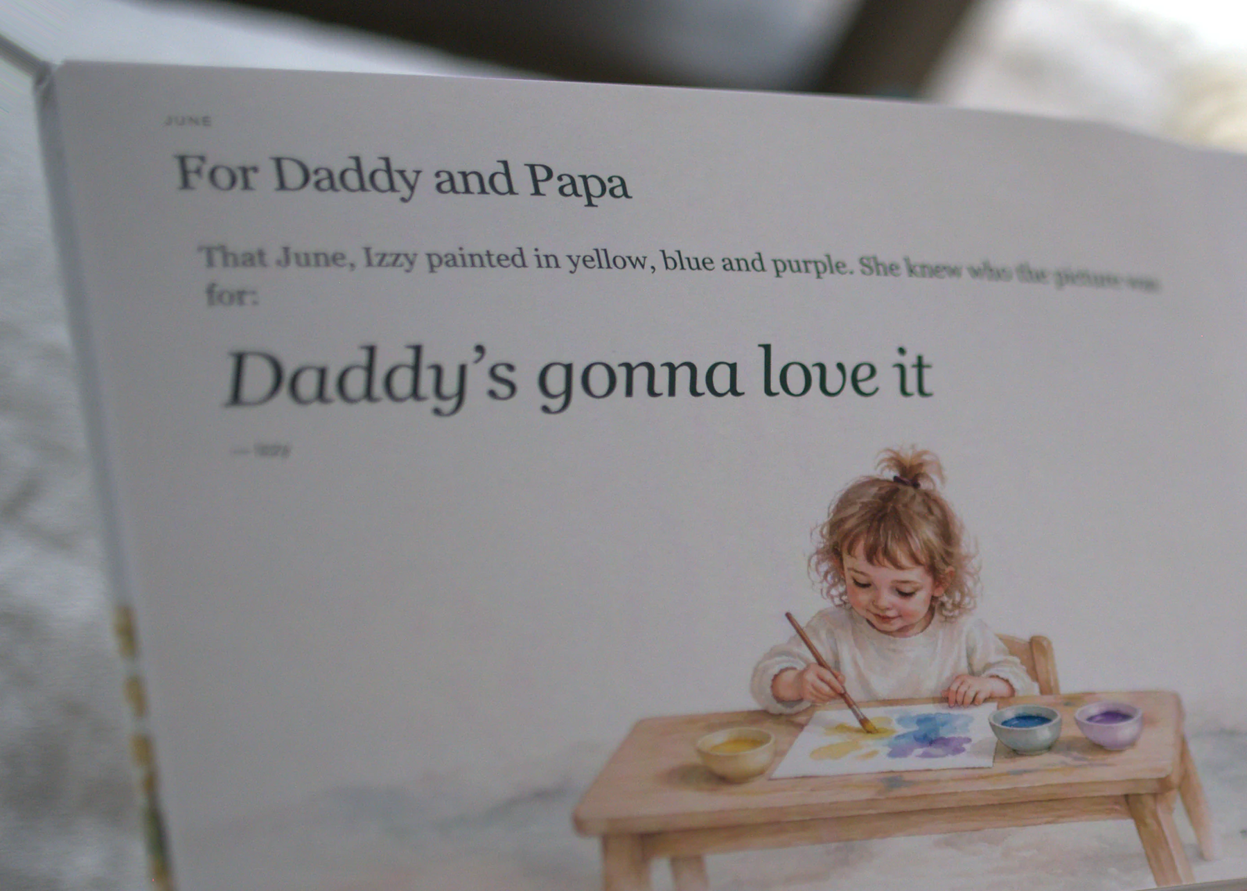 A page of Nicole&rsquo;s book, up close: a June note about Izzy painting a picture, her words, Daddy&rsquo;s gonna love it, and a watercolor of her at a little table with paint pots.