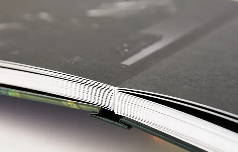 Side view of the layflat page block: thick lustre pages opening completely flat at the spine.